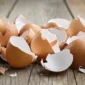 Cáscaras de huevo sobre una superficie de madera, subproducto utilizado para obtener la membrana de huevo (Eggshell Membrane, ESM) destinada a aplicaciones cosméticas.